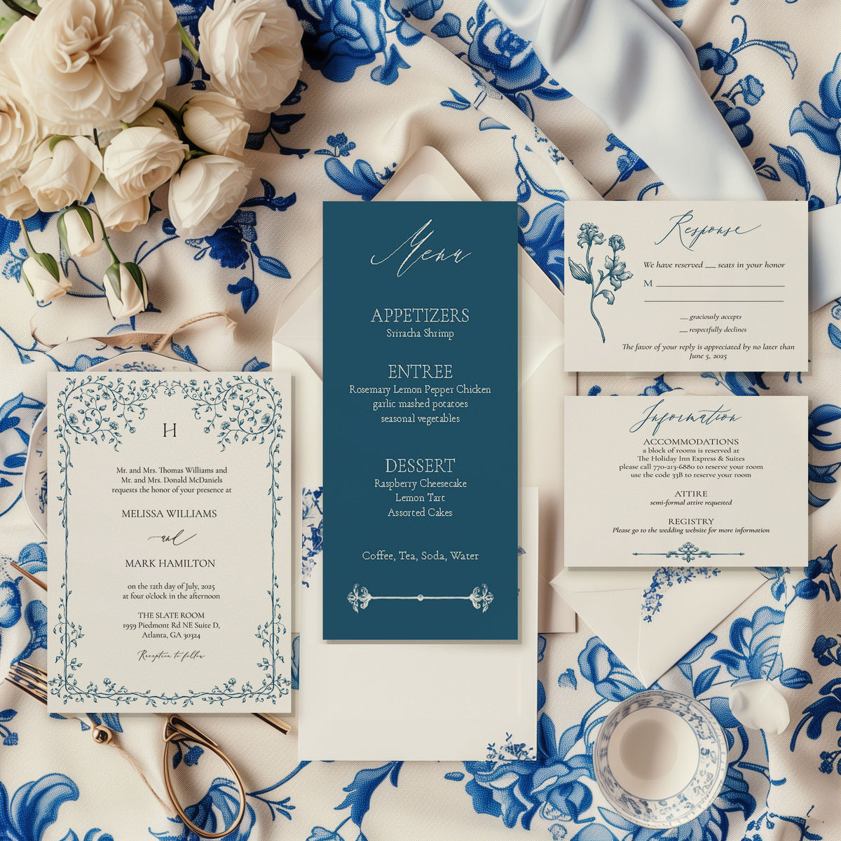 An elegant wedding invitation suite laid out on a table with blue floral patterns, including a save the date, invitation, RSVP, and information card, with a pocket fold on the side.