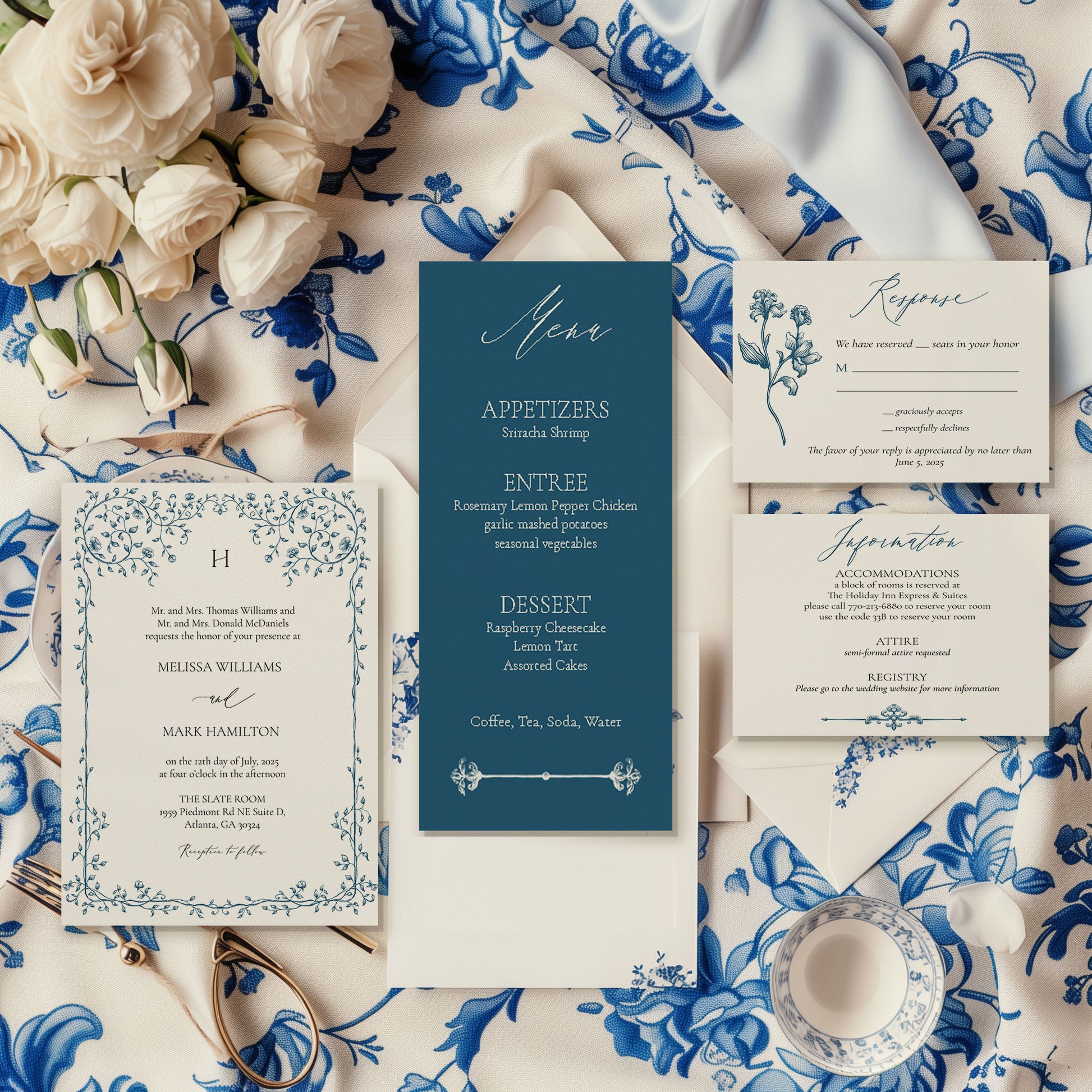 An elegant wedding invitation suite laid out on a table with blue floral patterns, including a save the date, invitation, RSVP, and information card, with a pocket fold on the side.