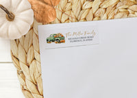 White envelope with fall-themed address label on a woven mat with pumpkins.