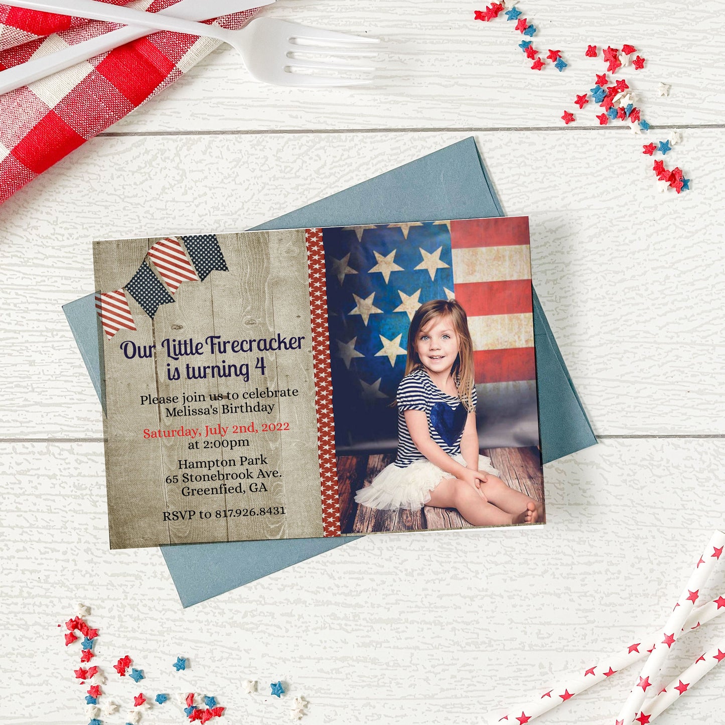 Invitation card with American flag design and photo of a child on a wooden surface with decorative items.