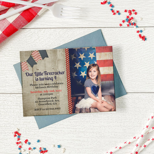 Invitation card with American flag design and photo of a child on a wooden surface with decorative items.