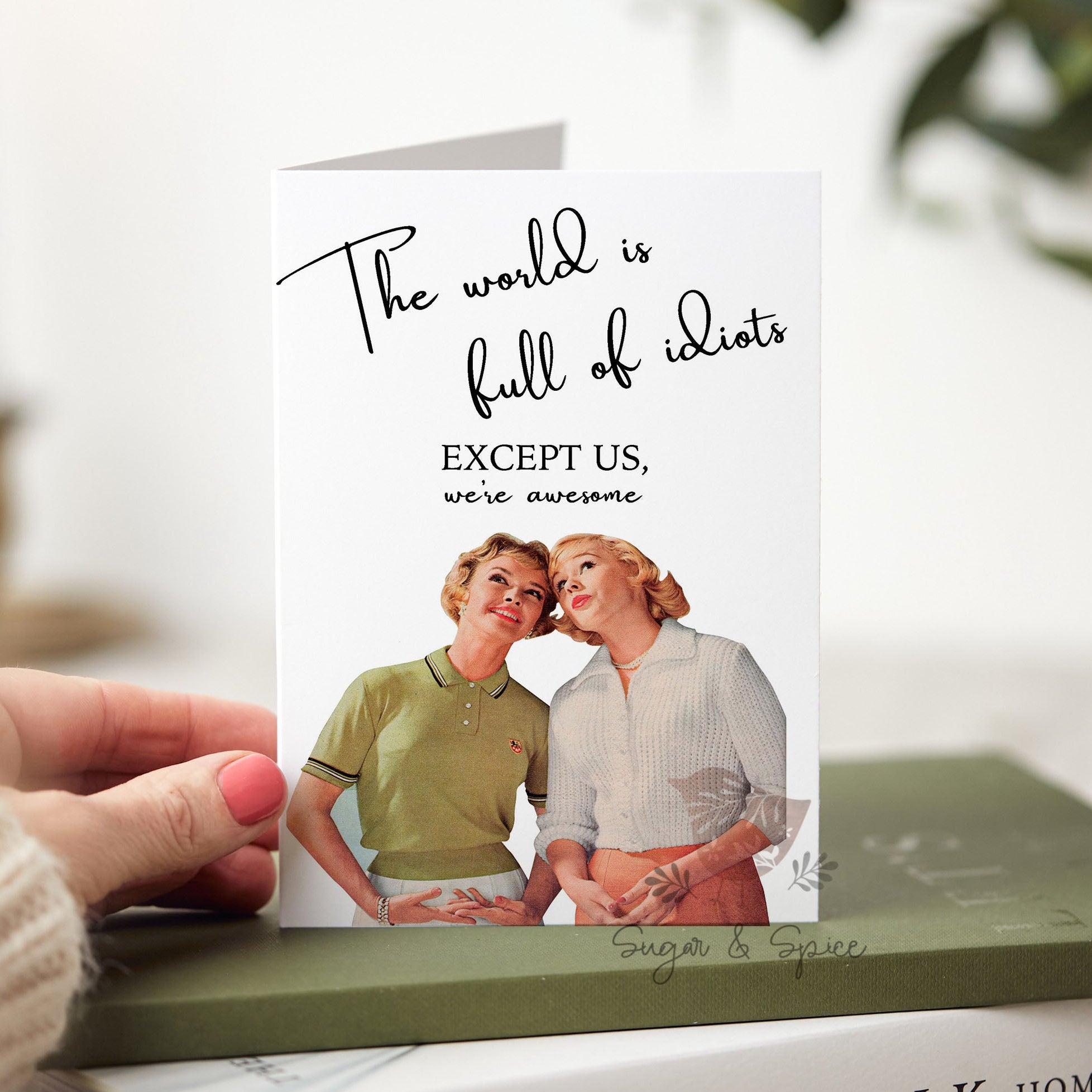 Person holding a card with a vintage-style illustration of two people and text, placed on a book.