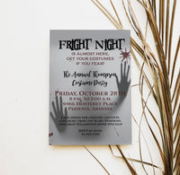A Halloween costume party invitation card styled on a white surface with dried palm leaves. The card is gray with black and burgundy text reading 'Fright Night' and includes silhouettes of hands holding a phone to their ear.