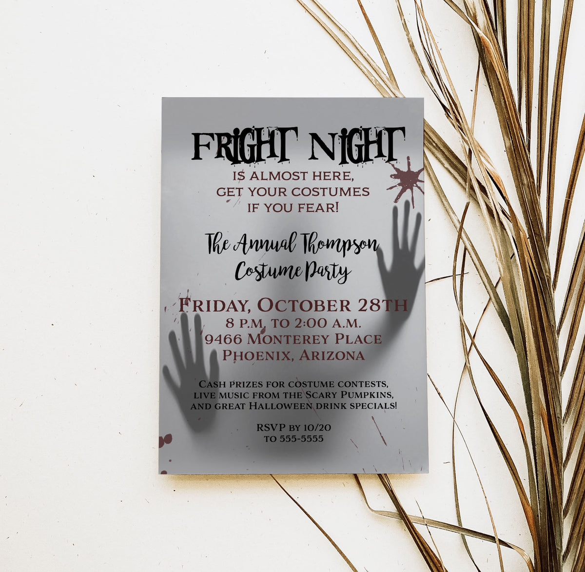 A Halloween costume party invitation card styled on a white surface with dried palm leaves. The card is gray with black and burgundy text reading 'Fright Night' and includes silhouettes of hands holding a phone to their ear.