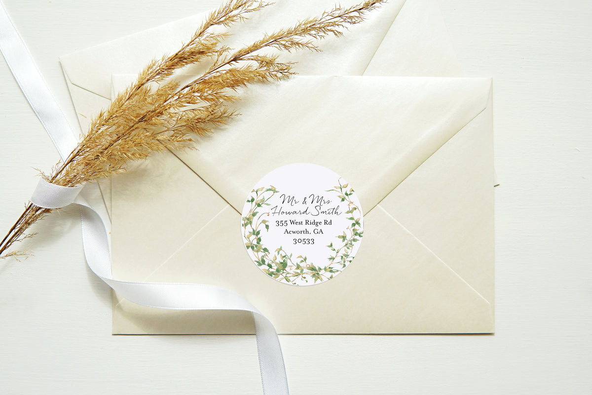 Cream-colored envelopes with a round botanical address label, tied with a white ribbon and styled with dried grass on a light background.