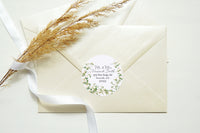 Cream-colored envelopes with a round botanical address label, tied with a white ribbon and styled with dried grass on a light background.