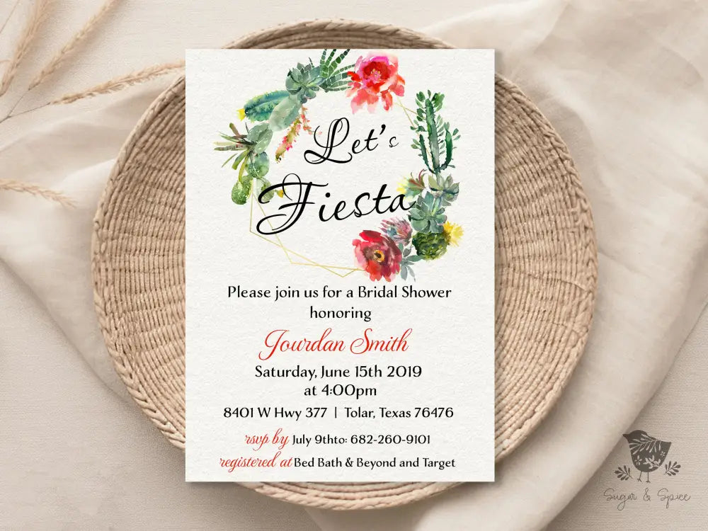 A bridal shower invitation with a floral design and the text 'Let's Fiesta' prominently displayed. The invitation is laid out on a woven table mat.