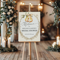 Bridal shower welcome sign on an easel with decorative candles and greenery in the background.
