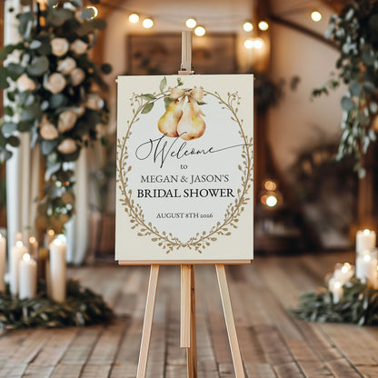 Bridal shower welcome sign on an easel with decorative candles and greenery in the background.