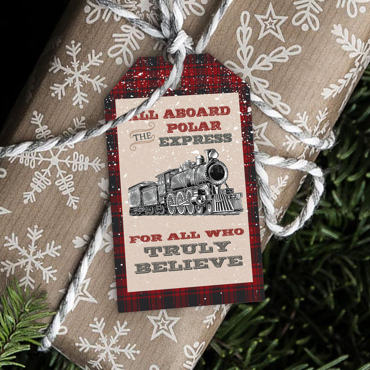 A Christmas-themed gift tag with a vintage steam locomotive illustration and the text 'ALL ABOARD THE POLAR EXPRESS FOR ALL WHO TRULY BELIEVE', attached to brown kraft paper wrapping with white snowflake patterns and twine, with pine branches in the background.