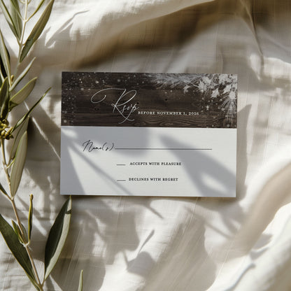 Wedding invitation card with RSVP details on a textured surface with greenery