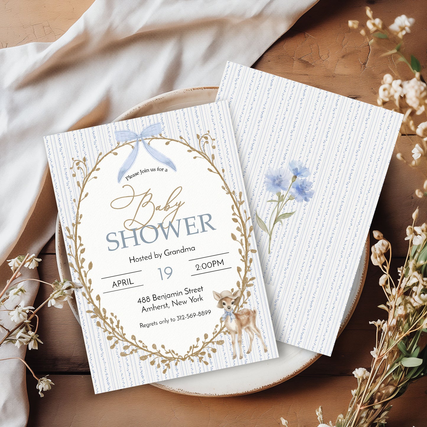 Baby shower invitation with floral design on a wooden surface