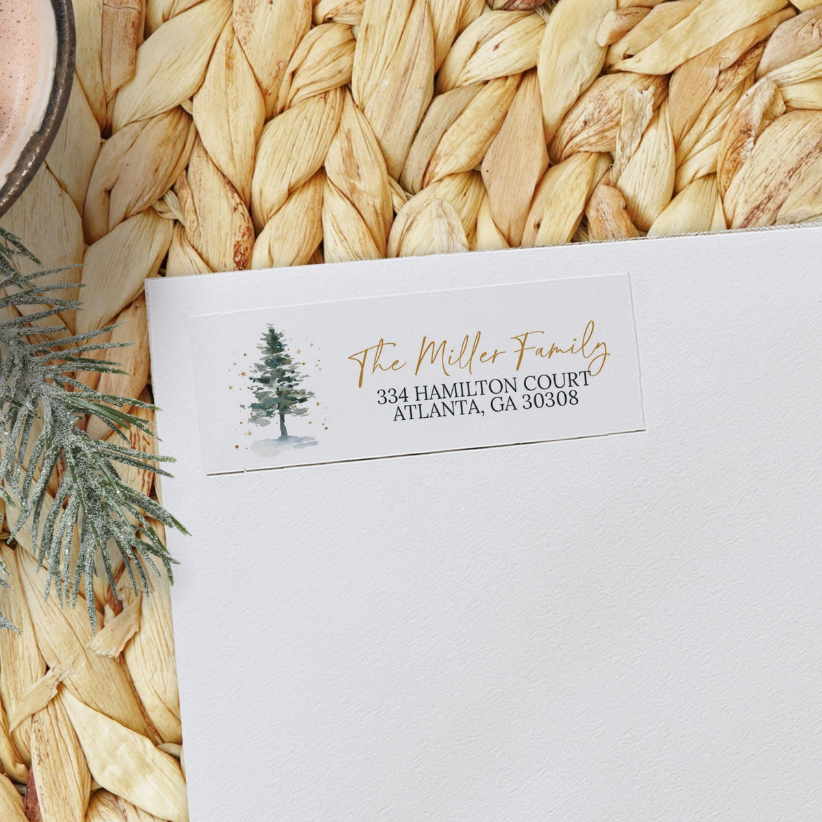 White envelope with personalized address on a woven mat with a hot chocolate and marshmallow in the background