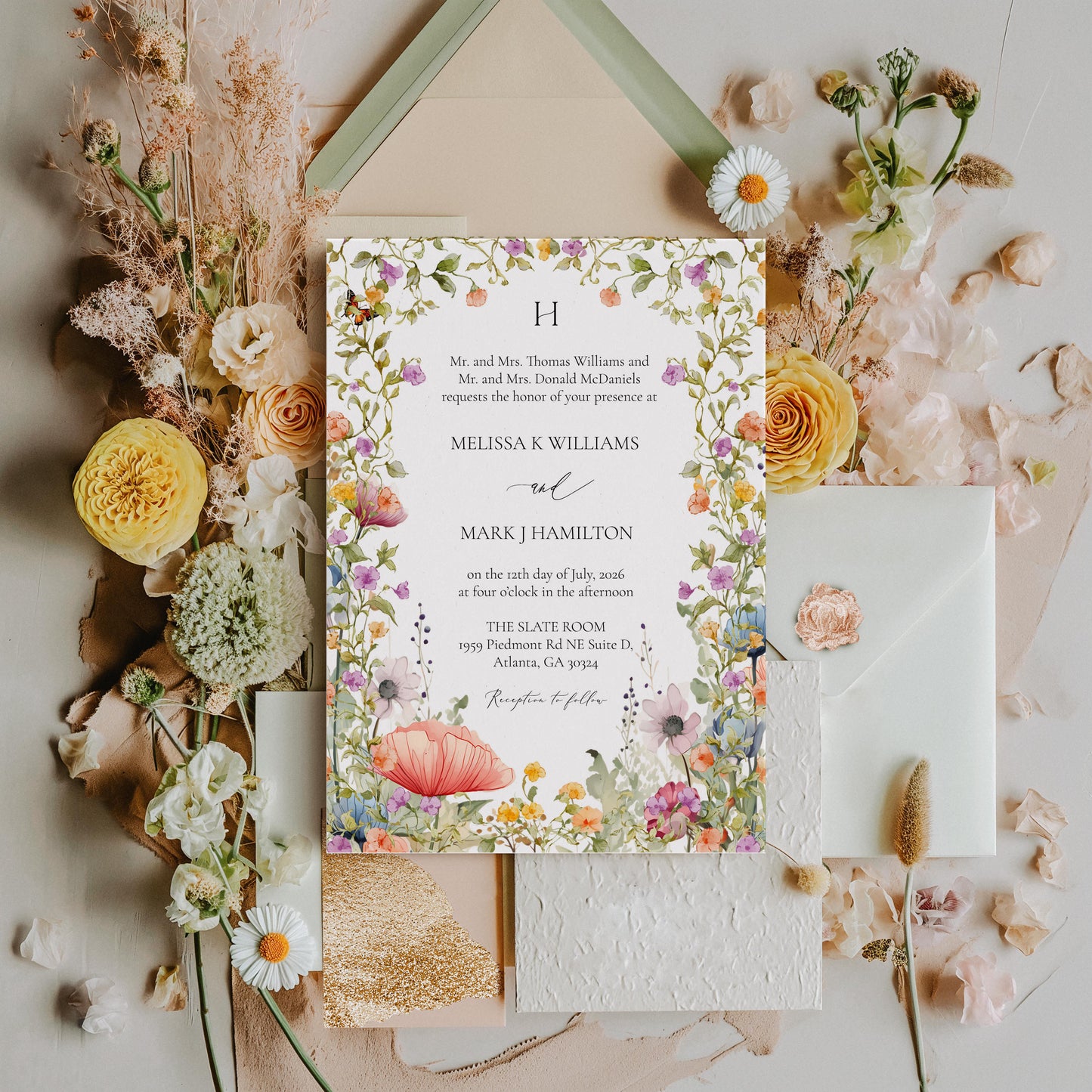 Floral wedding invitation with dried flowers and a gold envelope on a white background