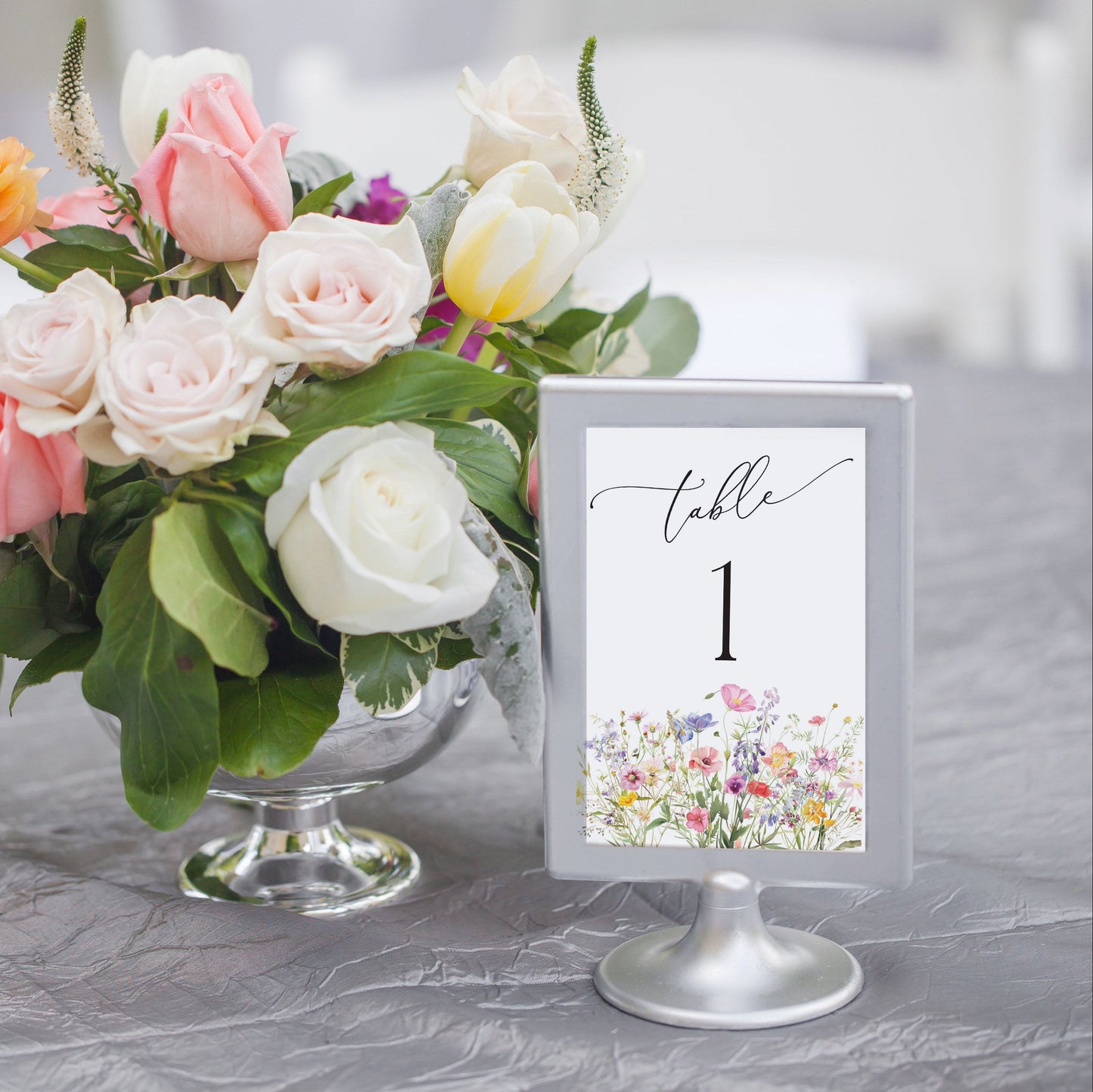 Floral arrangement in a glass vase with a table number card on a gray surface